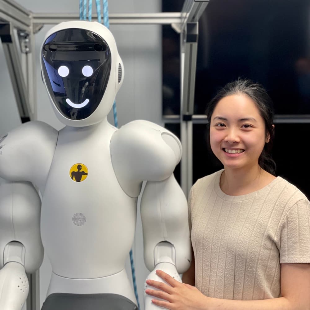 A smiling humanoid collaborative robot standing next to an engineer
